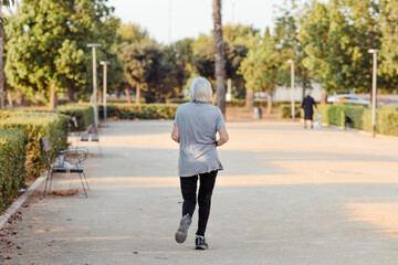 older woman running in a park with her back to the camera