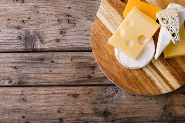 Foto op Plexiglas Overhead view of various cheese on wooden board at table, copy space © wavebreak3