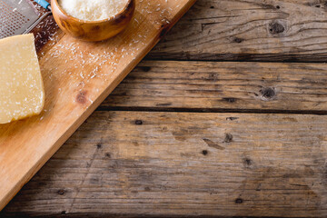 High angle view of cheese and grater on wooden board, copy space