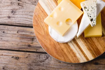  Directly above shot of various cheese on wooden board at table, copy space © wavebreak3