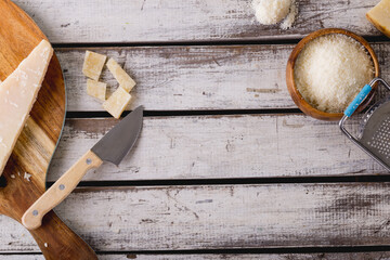Overhead view of grated cheese with grater and knife on wooden table, copy space - Powered by Adobe