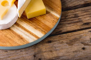 Tuinposter High angle view of various cheese on wooden board at table, copy space © WavebreakMediaMicro