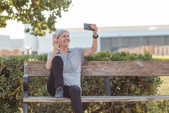 elderly woman smiles making gestures to a mobile phone that she carries in her hand