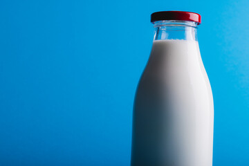 Close-up of milk in glass bottle against blue background with copy space