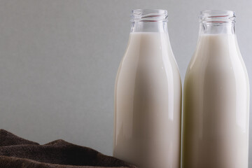 Close-up of milk in glass bottles against gray background with copy space