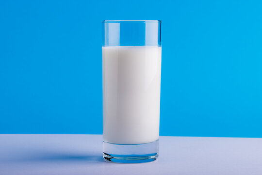 Close-up of milk glass on table against blue background with copy space