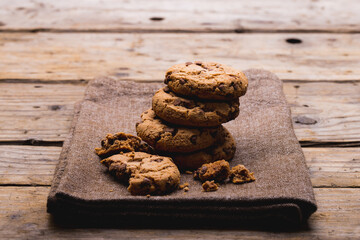 Cookies stacked on burlap at wooden table with copy space