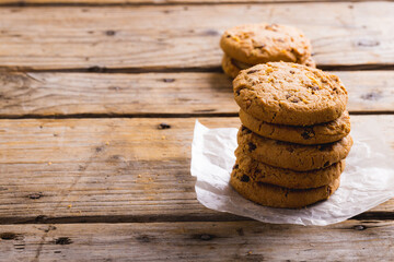Cookies stacked on parchment paper at wooden table, copy space - Powered by Adobe