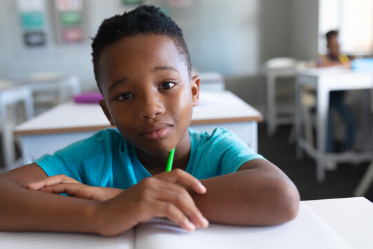 Portrait of african american elementary schoolboy sitting at desk in classroom