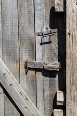 fragment of an old wooden door closed with a bolt