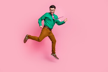 Fototapeta na wymiar Full length photo of positive lucky man dressed green shirt eyewear jumping high empty space isolated pink color background