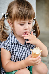 Little baby girl eating ice cream, licking her fingers