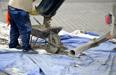 Men in work clothes, midreé colors. concrete mixer. truck chute trough, pouring, concrete into...