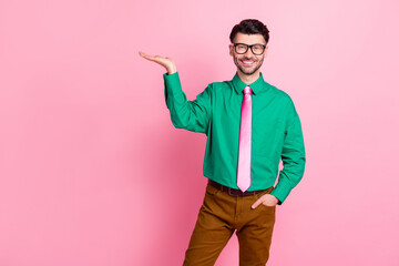 Portrait of young stylish guy wear green shirt pink tie holding hand new product advertisement...