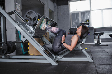 Full length shot of a sportswoman exercising at the gym on leg press machine, copy space