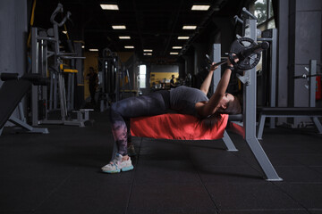 Fototapeta na wymiar Full length shot of a fitness woman doing bench press at sports studio