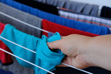 female hands hang wet clothes close-up, laundry hanging and drying on wire room dryer, home chores...