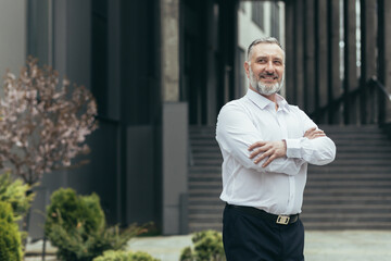 Portrait of successful turkish businessman investor, man outside office building wearing shirt and...