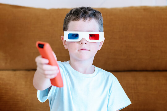 Boy in 3D glasses changing channels with remote controller