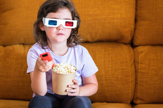 Girl in 3D glasses with popcorn watching movie