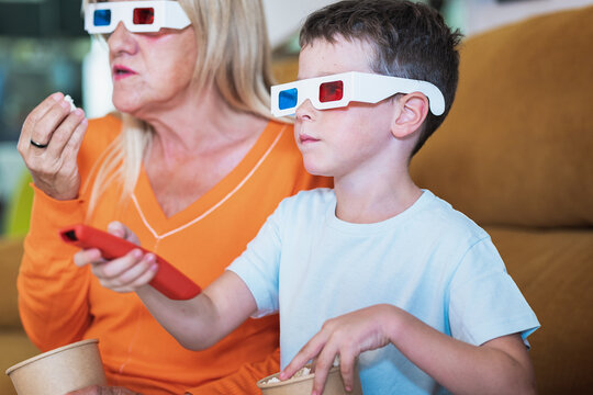Boy in 3D glasses changing channels near mother