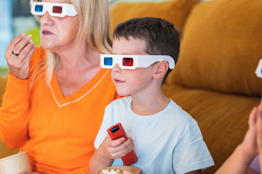 Boy in 3D glasses changing channels near mother