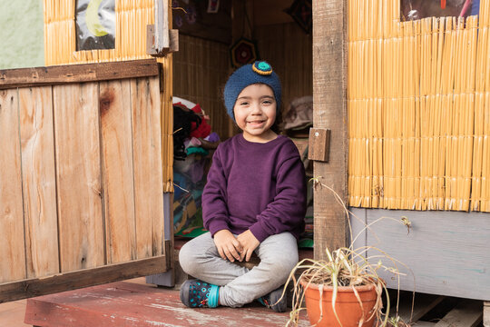 Cheerful ethnic child sitting on porch in countryside