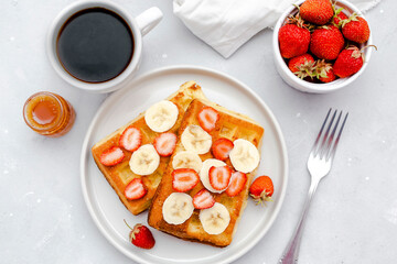 Square belgian waffles with strawberries berries,bananas,condensed milk,honey on plate, cup of coffee espresso. Tasty breakfast, sweet dessert food.selective focus, close up top view flat lay