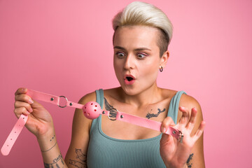 Sexy girl looking with surprised face at pink gag while preparing playing pervert fetish game - obrazy, fototapety, plakaty