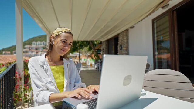 Pleased woman tourist enjoying morning coffee while sitting on terrace with sea view on Turkish resort, using laptop computer for remote work, freelance concept. slow motion 4k
