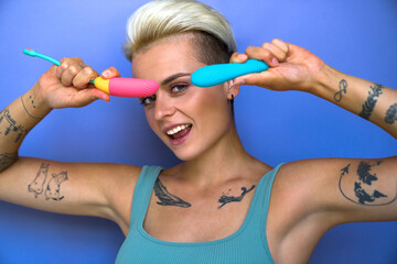 Short haired girl in domestic clothes posing with two vibrator for clitoral vaginal stimulation - obrazy, fototapety, plakaty