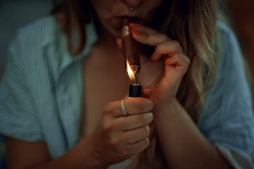 Close-up shot of a female lighting her cigar with blurred background