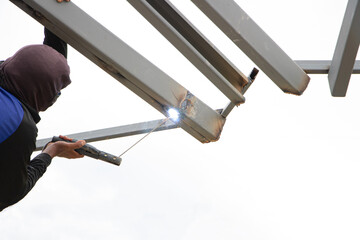 Welders work on roof trusses without safety equipment, safety concept.
