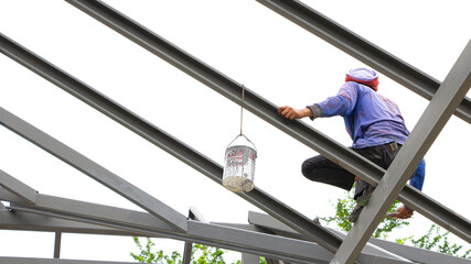 Painters work on roof trusses without safety equipment, safety concept.