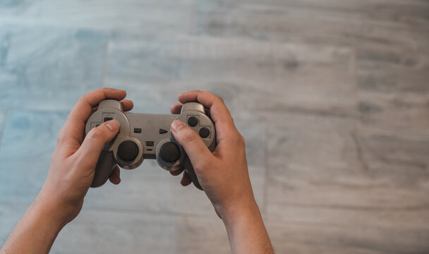 Detalle de mano manejando un mando de consola. Fotografía horizontal, con espacio para texto.