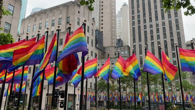 Footage of several pride flags in front of buildings being blown by the wind