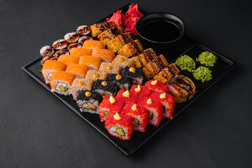 Traditional japanese food - sushi, rolls and sauce on a dark background