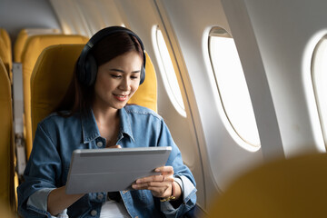 Beautiful asian travel woman watching movie on digital tablet in airplane - obrazy, fototapety, plakaty
