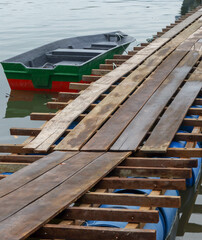 small fishing boat at traditional wooden jetty on the calm river
