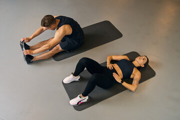 Attractive man and woman athletes performing sit ups on yoga mat