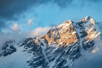 Beautiful sunset in the  snow covered mountains and fog, blue sky with  clouds.