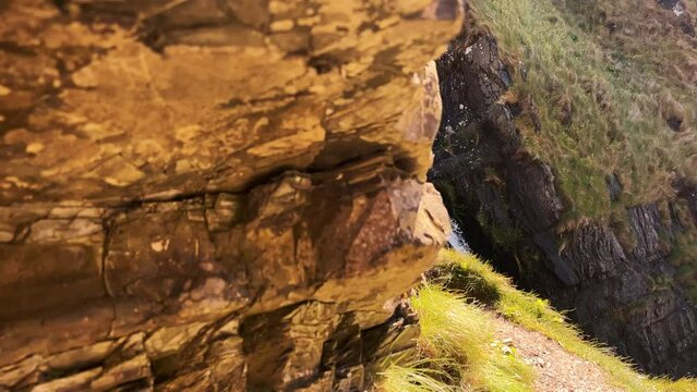 Top view of Speke's Mill Mouth waterfall runs through the cliffs on a sunny day