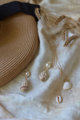 straw hat on the table next to earrings and pendant