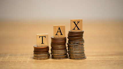 Wooden blocks with the word TAX on stacked coins. concept of income tax.