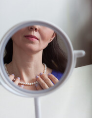 The face of a middle-aged woman is reflected in the mirror