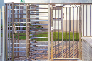 Protected entrance gate - secured turnstiles outdoors. Steel revolving turnstiles at the entrance of production or metro station. Closeup of steel revolving security turnstile on the street