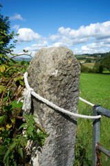 an old frayed rope attached to an ancient stone gate post, holding closed a metal gate