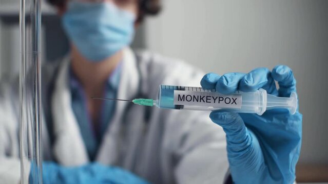 Outbreak of type smallpox disease. Monkeypox research search for effective vaccine. Woman's hand in gloves holds syringe inscription monkeypox. Phrase MONKEYPOX on syringe. Medicine pandemic concept