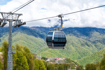 Aerial lift against the backdrop of a green forest and snow-capped mountains