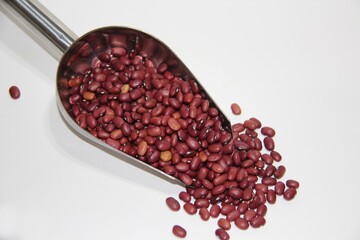 Kidney beans, red beans in a stainless steel measuring spoon on white background, top view with copy space.